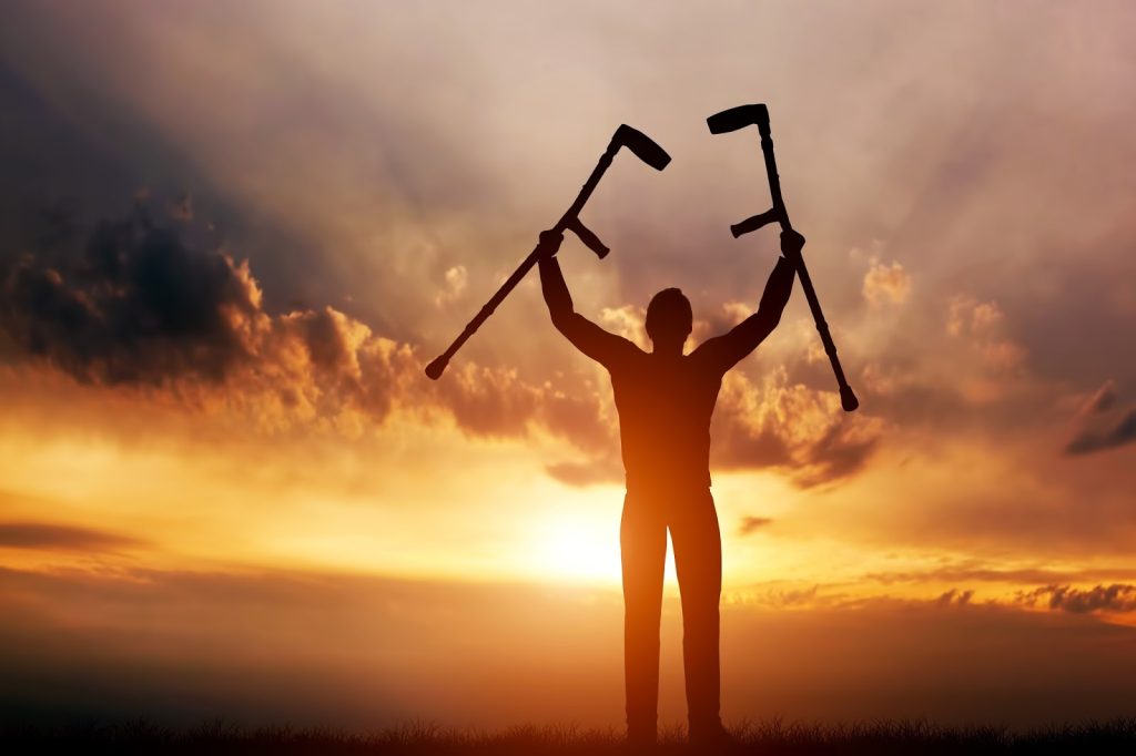 Person, Obscured by Sunlight, Holding Crutches Up, Symbolizing the Strong Belief of OFM Houston Members